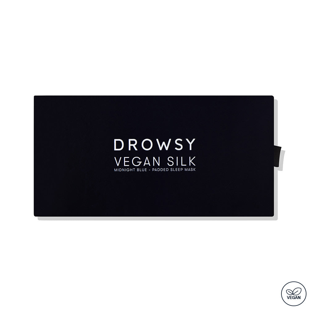 A rectangular black box with "Midnight Blue - Vegan Silk Sleep Mask" by drowsysleepco in white text. The organic vegan sleep mask features a small vegan certification logo in the bottom right corner.