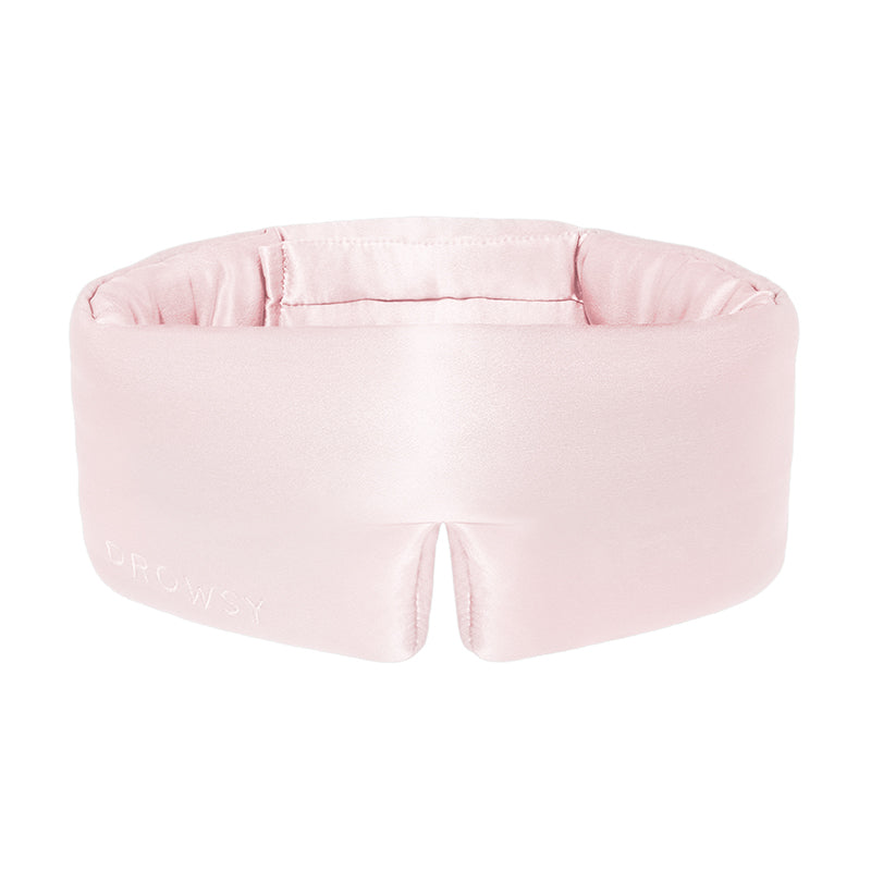 The Petal Pink sleep mask by us.drowsysleepco is a light pink, padded silk eye mask with a wide seamless band and “DROWSY” embroidery. This plush blackout mask fully covers your eyes for uninterrupted beauty sleep.