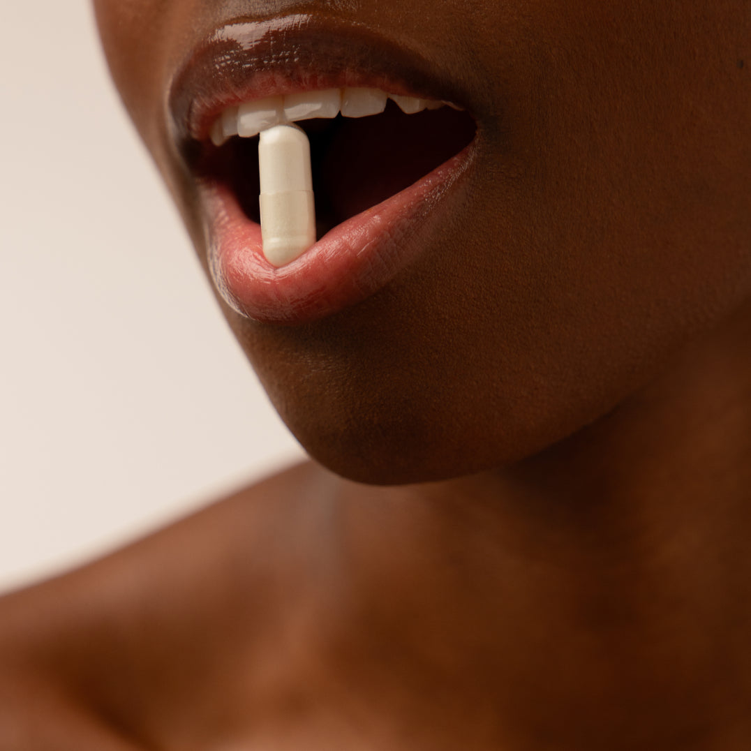A close-up of a person’s mouth slightly open with a white capsule resting between their lips, set against a neutral background—evoking the restorative promise of drowsysleepco’s Supplements - Sleep & Glow Protocol.