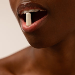 A close-up of a person’s mouth slightly open with a white capsule resting between their lips, set against a neutral background—evoking the restorative promise of drowsysleepco’s Supplements - Sleep & Glow Protocol.