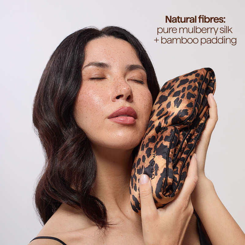 A woman with closed eyes holds the Hotel Paradiso Wild Thing Sleep Mask by us.drowsysleepco, crafted from pure mulberry silk and bamboo padding. Text highlights natural fibres, comfort, relaxation, and better skin hydration.