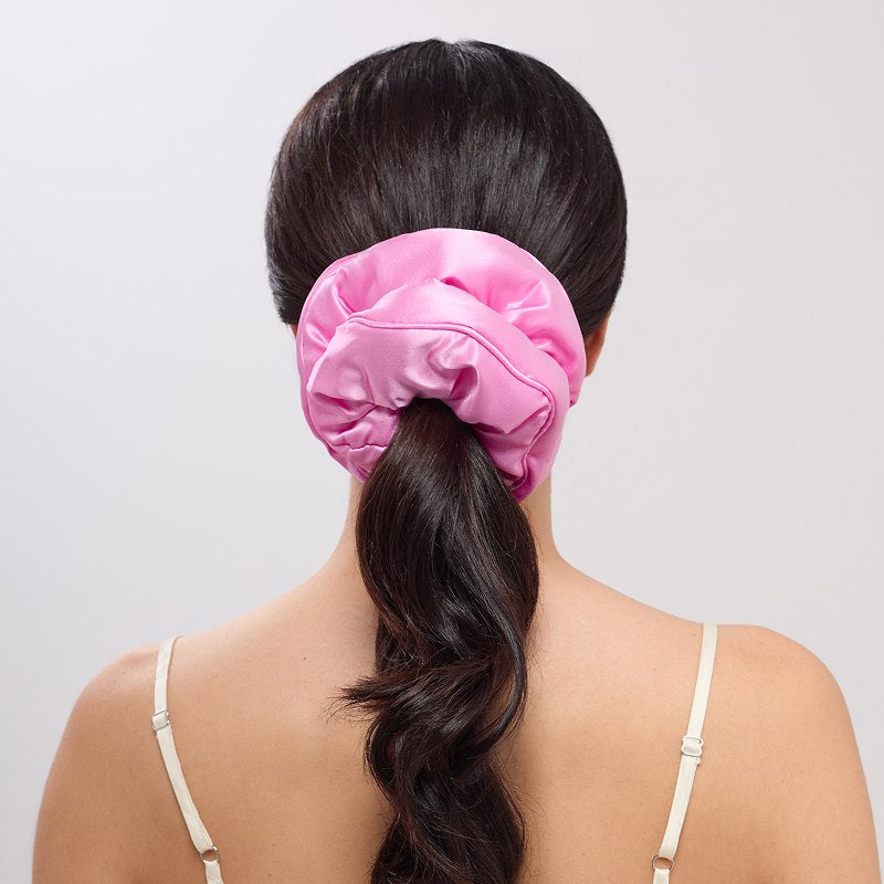 A person with long, dark hair in a low ponytail secured with the us.drowsysleepco Hotel Paradiso - Heatwave Padded Scrunchie, seen from behind. They're wearing a light, thin-strapped top against a plain background.