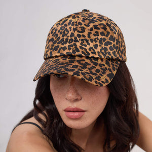 A woman with dark hair wears the Drowsy Silk Cap - Hotel Paradiso Wild Thing by Drowsy, a brown and black leopard print cap for hair protection, along with a black strap top. She looks slightly downward with a neutral expression.